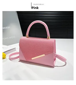 Détail du sac à main rose avec rabat tissé rouge et blanc et barre métallique