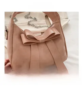 Detail view of large decorative bow on nude pink leather handbag with silver chain strap