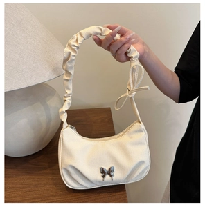 Détail du sac croissant en toile crème avec poignée plissée et papillon en métal argenté