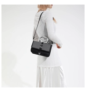 Detail of trendy black crossbody bag with unique silver mirror textured metal handle