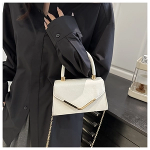 Detail of white glitter handbag featuring elegant V-shaped gold hardware and chain strap