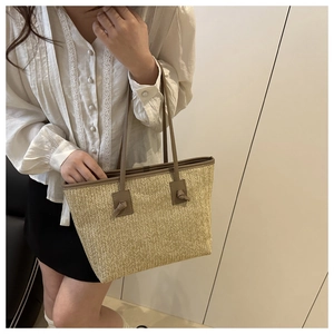 Detail of woven straw tote bag with V-shaped texture and brown faux leather shoulder straps