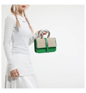 Detail of contrast color handbag with silver metal handle and woven texture flap cover