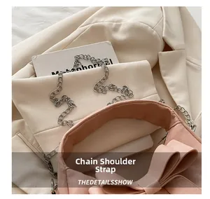 Detail of pink crossbody bag featuring a large bow and silver metal chain strap