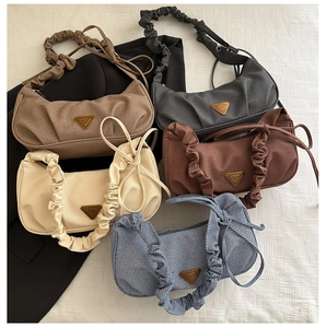 Close-up of pleated shoulder straps and metal triangular detail on textured armpit bags