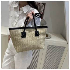 Detail showing the woven texture and black handle knots of this straw tote bag