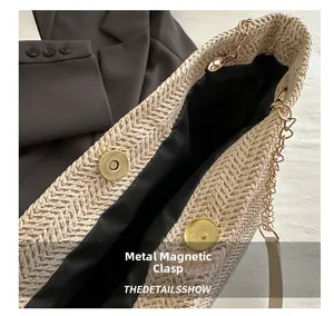 Detail of golden magnetic snap closure and chain strap on woven straw tote bag
