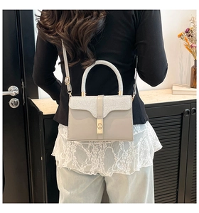 Detail of elegant crossbody bag with metallic lock shown on model in home setting