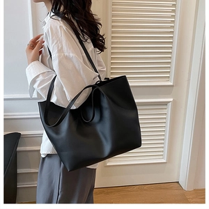 Detail of the minimalist large black PU leather tote bag with slim shoulder straps