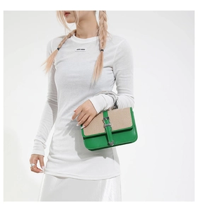 Detail of green leather and beige woven fabric contrast on a metal handle handbag