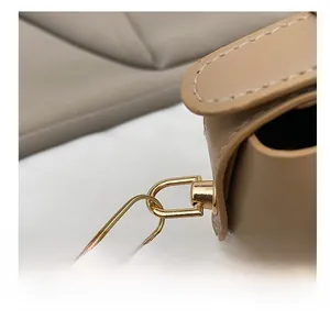 Detailed close-up of golden metal swivel hook and fine stitching on khaki leather bag
