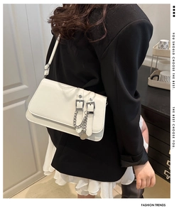 Détail du sac à bandoulière minimaliste en cuir beige avec boucles et pendentif chaîne