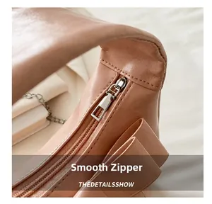 Close-up of smooth metal zipper and decorative bow on dusty pink dumpling bag