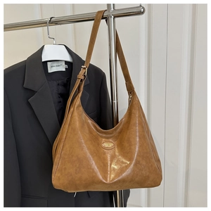 Detail of caramel brown faux leather tote with embossed logo on a hanger