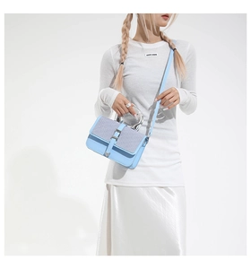 Detail showing light blue leather and tweed paneling on a stylish crossbody handbag