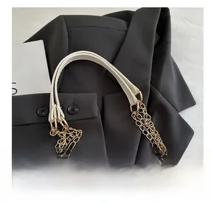 Detail of straw tote bag showing white leather strap with elegant gold chain accents