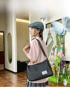 Close-up of black canvas crossbody bag featuring a white decorative label on a model