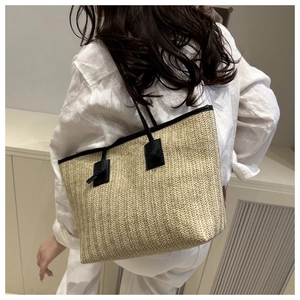 Detailed close-up of straw tote bag showing tight weave texture and black leather strap