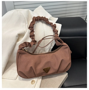 Detail view of the brown corduroy shoulder bag with pleated handle and metal logo
