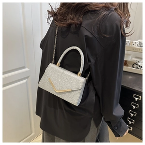 Detail of silver glitter crossbody bag with gold V-decoration and chain strap