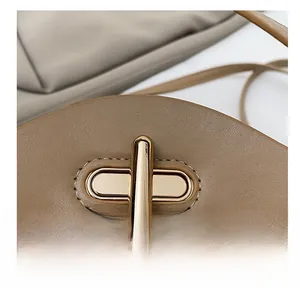 Detailed close-up of premium golden oval turn-lock and pebbled leather texture on handbag