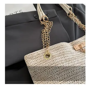 Detailed macro view of beige woven tote bag with metallic grommets and chain strap