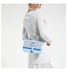 Detail of blue leather shoulder bag with purple woven panel and silver wavy handle