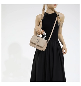 Detail of woven texture flap and silver U-shaped metal handle on a beige crossbody bag