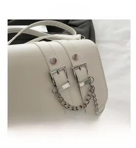 Close-up of the stylish off-white shoulder bag featuring silver buckles and metal chain detail