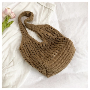 Flat lay of brown crochet tote bag with hollow knit texture and pink tulip on white fabric