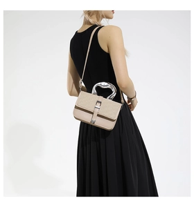 Detail of cream contrast bag with heart-shaped metal handle shown on a model in black dress