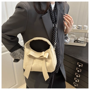 Sac à main beige chic avec nœud et bandoulière en chaîne dans un décor moderne