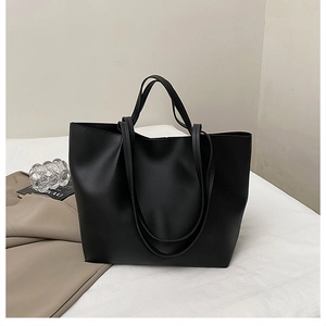 Detail of minimalist black tote bag on a white surface with lifestyle props for daily use