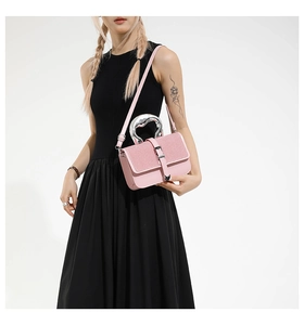 Detailed view of pink crossbody bag featuring a unique silver metallic handle decoration
