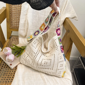 Hollow-out woven bucket bag with colorful floral embroidery on a vintage chair