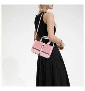 Pink crossbody bag with heart-shaped metal handle shown on a model in a black dress