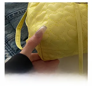 Detailaufnahme der herzförmigen Steppnähte auf der hellgelben PU-Oberfläche der Tasche