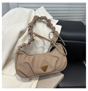 Macro detail of khaki pleated hobo bag fabric with a golden triangular logo