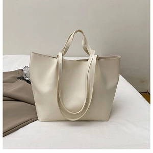Macro view of minimalist cream tote bag showing smooth leather texture and long straps