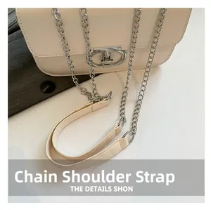 Detail der beigen Umhängetasche mit silberner Kette und einzigartiger Metallschnalle