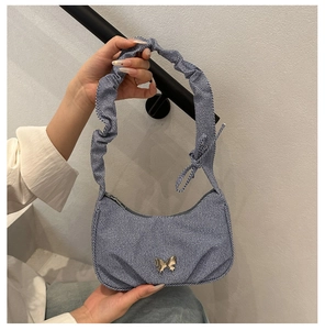 Détail du sac croissant en denim rayé bleu avec papillon en métal et bandoulière plissée