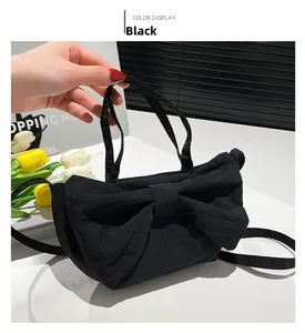 Detail of black tote bag featuring oversized bow decoration and ruched fabric texture
