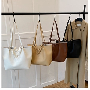 Display of four PU leather tote bags in white, beige, brown, and black hanging on a rack