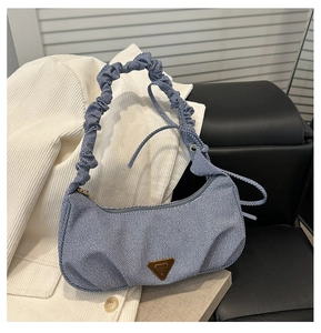 Detailed shot of light blue denim shoulder bag with gathered handle and metal plate