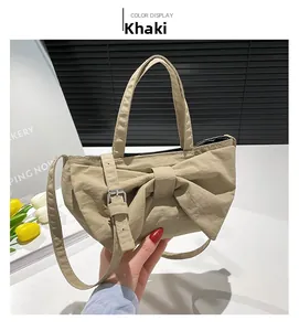 Detail of khaki bow handbag featuring washed fabric texture and adjustable shoulder strap