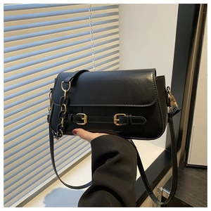 Close-up of black crossbody bag with gold buckles and matte-finish chain strap details