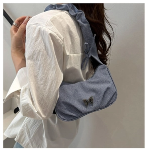 Close-up of blue striped underarm bag with metal butterfly buckle and ruffled strap