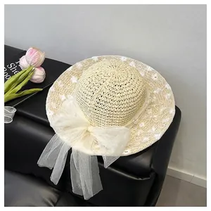 Close-up of straw bucket bag featuring white lace embroidery and large mesh bow with pearls