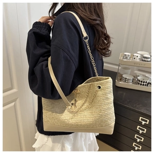 Détail du sac cabas beige tissé avec bandoulière chaîne dorée et pendentif cerf