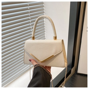 Detail of elegant beige crossbody bag with gold V-shaped metal trim and chain strap